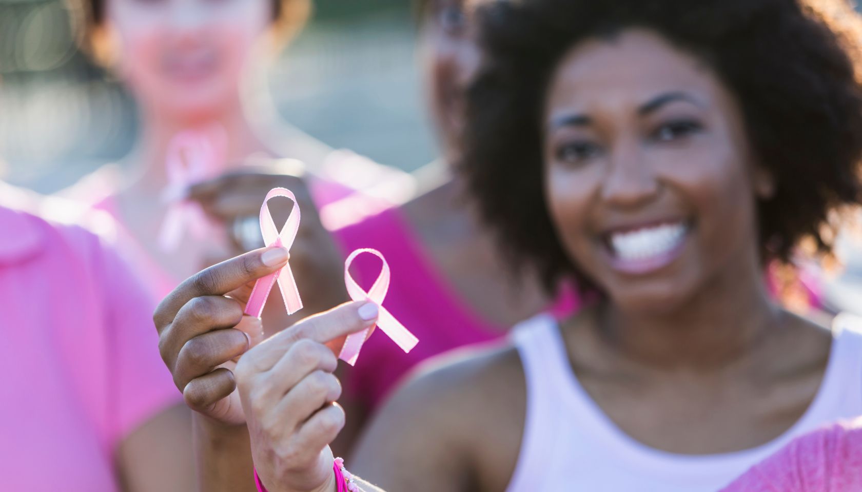 Multiracial women holding breast cancer awareness ribbon