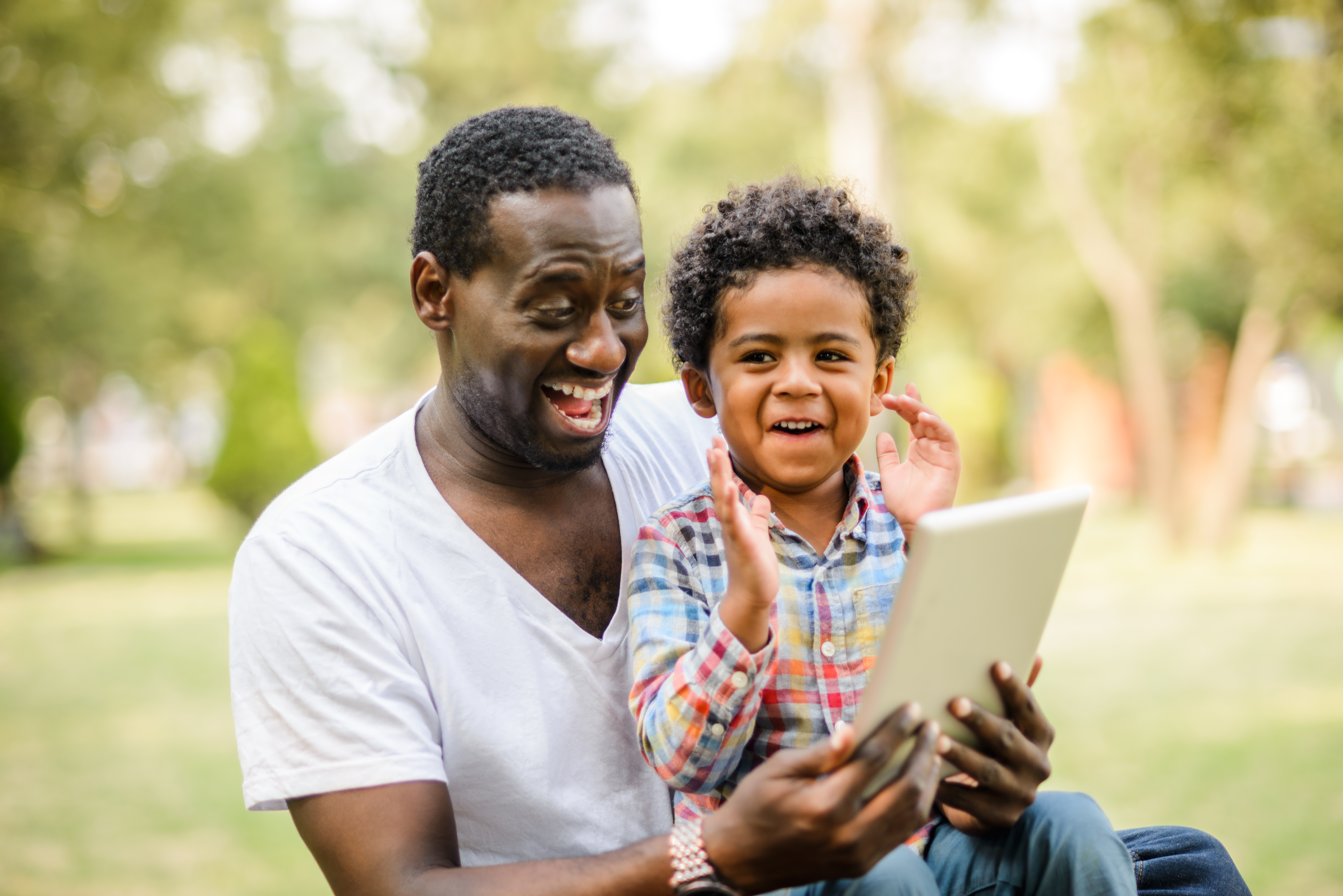 Father and son playing game on digital tablet.