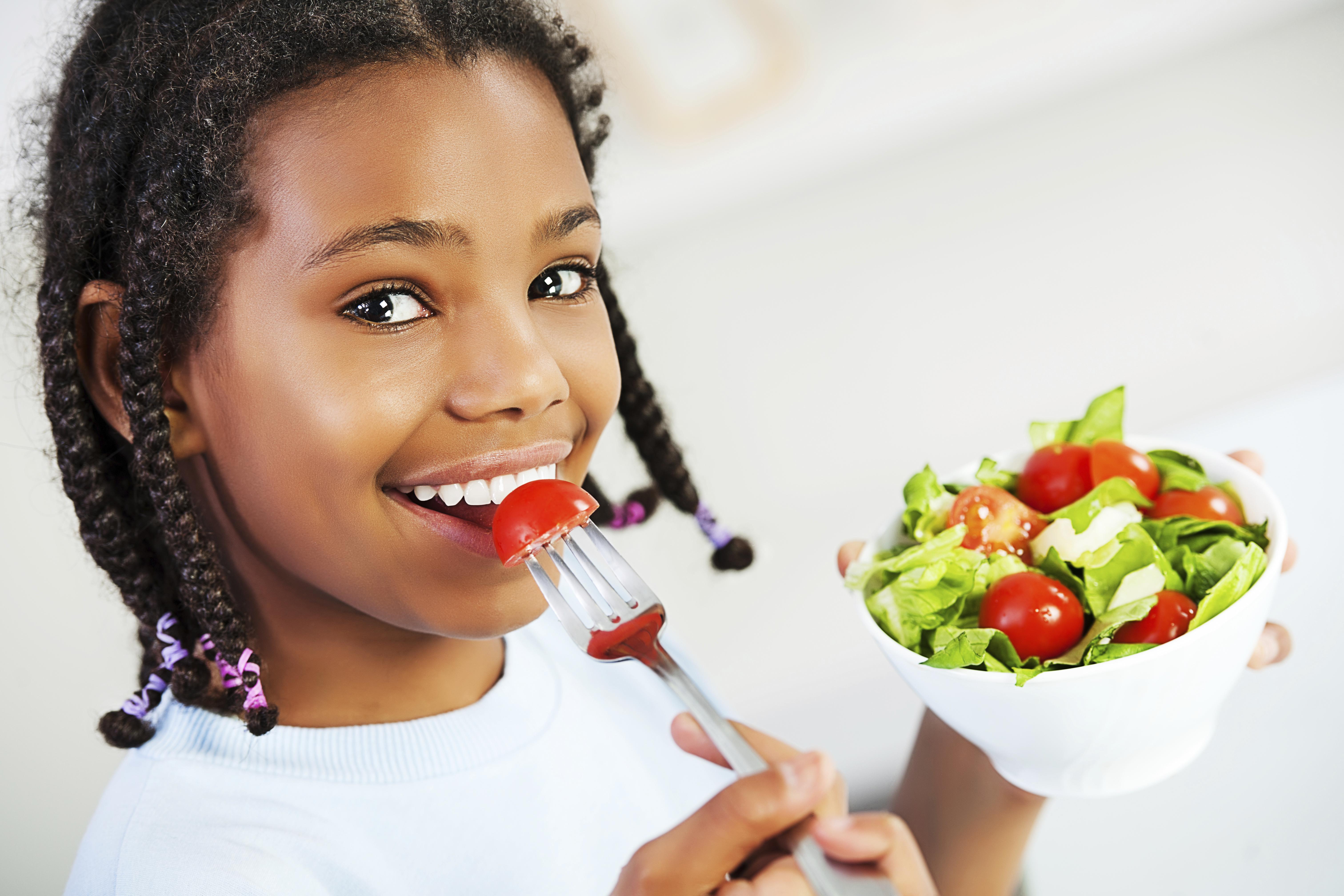 Little girl eating vegetable salad.