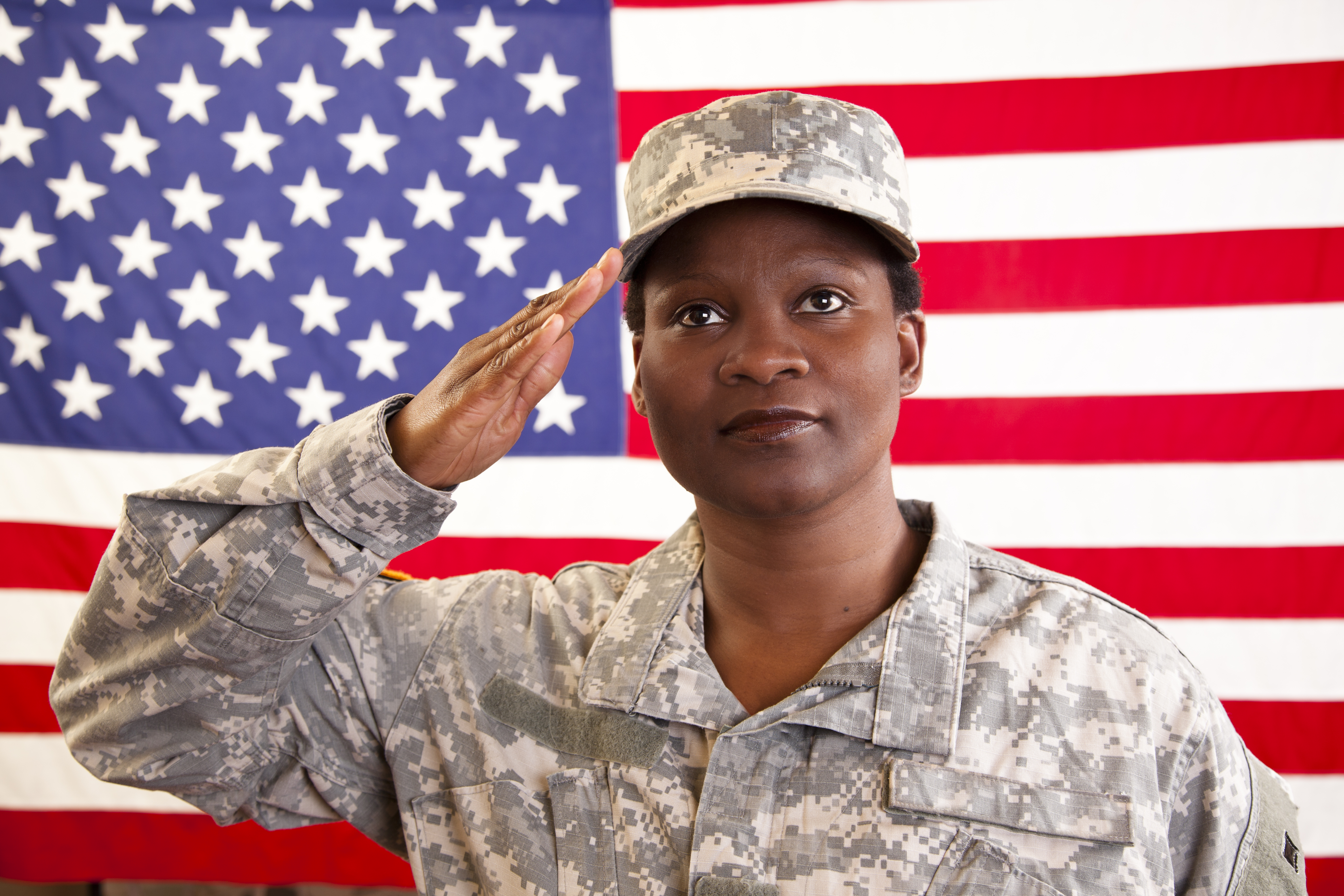 African descent military woman salutes American flag.