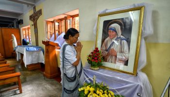A Christian devotee prays infront of the picture of Saint...
