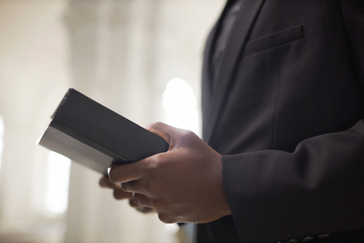 Black Priest Holding Bible in Hands