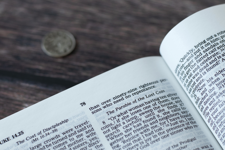 Lost coin parable verses in open holy bible book placed on wooden background
